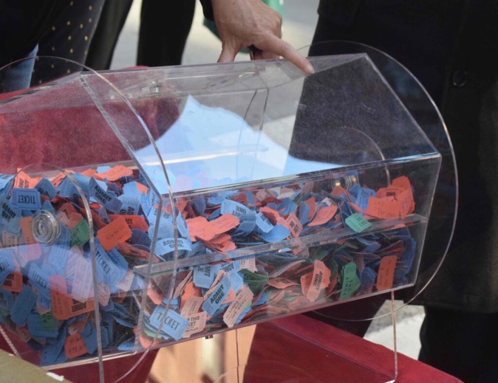 Clear plastic rotating drum filled wih blue and red raffle tickets.