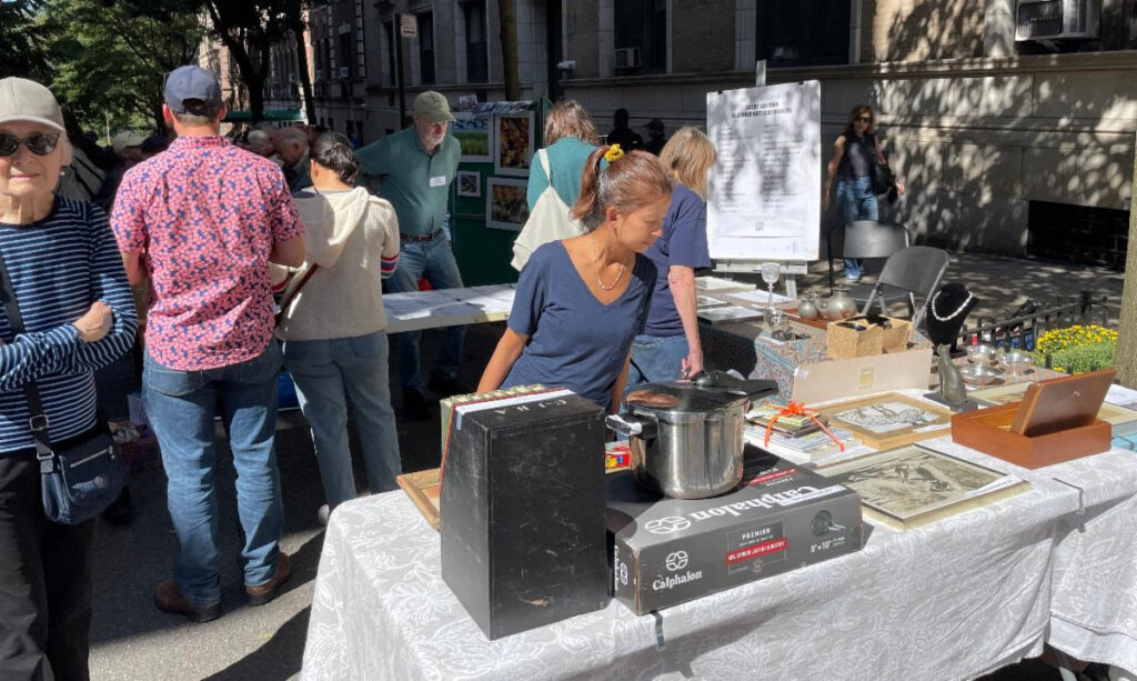 A woman in a blue t-shirt and ponytail peruses items at the Silent Auction table as others behind her her do the same.