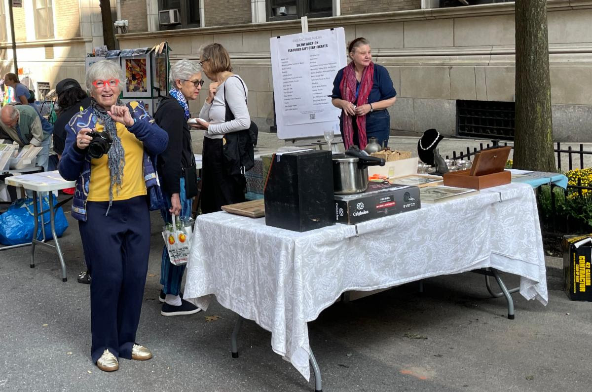 Street scene: Sidewalk Table with white tablecloth showcasing items from the Silent Auction