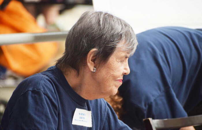 An elderly woman with short steel gray hair and a navy t-shirt smiles im profile.