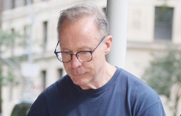 A middle aged man in glasses and a navy West 104th Street t-shirt