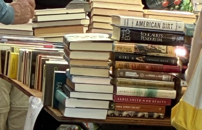 A table piled with books including American Dirt and Foucault’s Pendulum